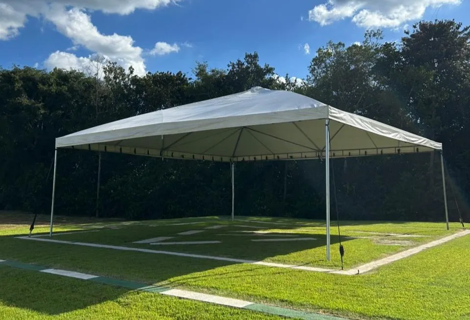 Tenda piramidal montada em área gramada ao entardecer